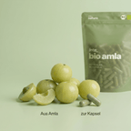 Frische indische Stachelbeere (Amalaki) neben den Bio Amla Kapseln