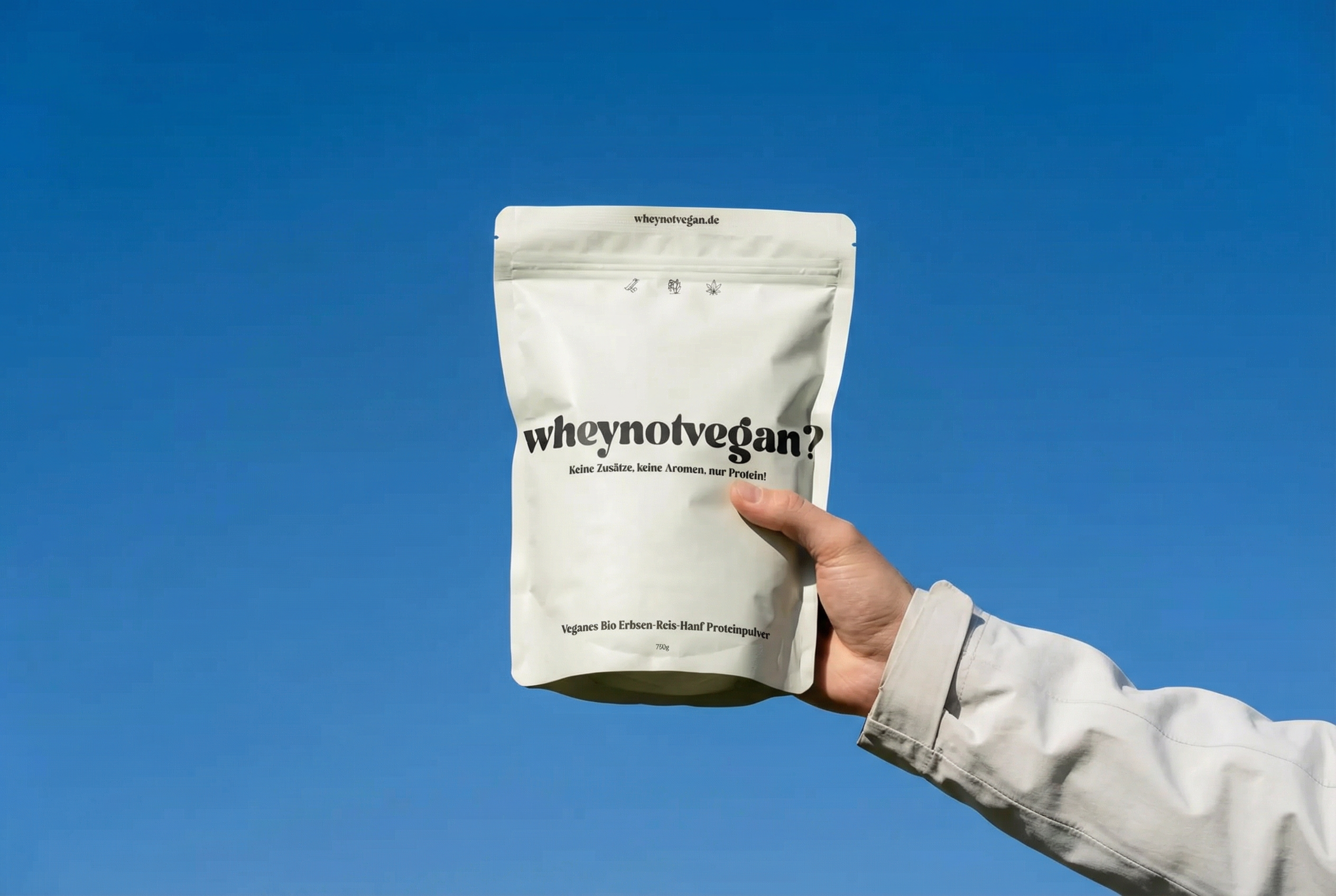 Eine Hand hält eine 750-g-Packung veganes Bio-Proteinpulver aus Erbse, Reis und Hanf vor blauem Hintergrund